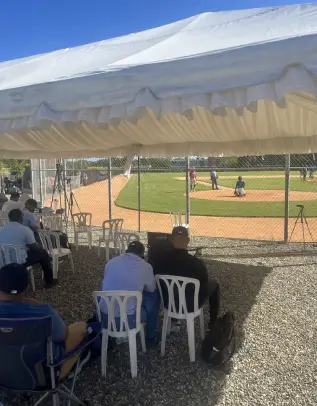 spectators in plastic chairs watch the baseball game